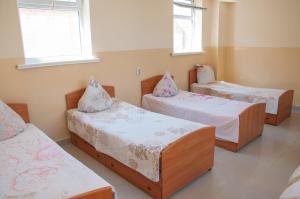 a room with three beds and two chairs at Sakura Guesthouse in Bishkek