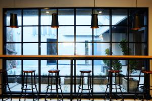 a bar with stools in front of a large window at Livinn Hostels Gubeng Station Surabaya in Surabaya