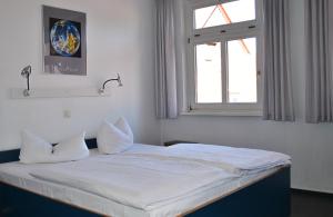 a bedroom with a bed with white sheets and a window at Pension Töpferhof in Tangermünde