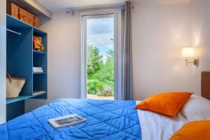 a bedroom with a blue bed and a window at Camping Piantelle in Moniga