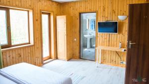 a room with wooden walls and a television and a bedroom at Vila Far in Sfântu Gheorghe