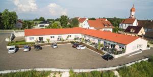 a large white building with cars parked in a parking lot at L-Appartements in Burgau