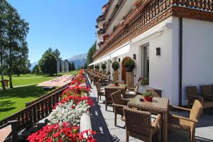 eine Reihe von Tischen und Stühlen auf einem Gebäude mit Blumen in der Unterkunft Grand Hôtel du Golf & Palace in Crans-Montana