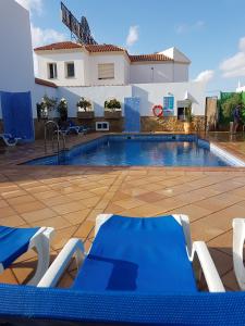 a swimming pool with chairs and a house at Hostal Manolo in Garrucha