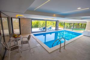 a swimming pool in a house with a table and chairs at Villa Glamour in Hadžići