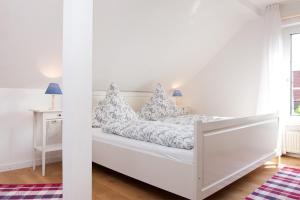 a white bedroom with a bed with pillows on it at Landhaus Lillesand in Esens +18 photos