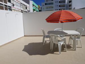アルマカオ・デ・ペラにあるBeira Mar Terrace Apartmentのパティオ(パラソル付きのテーブルと椅子付)