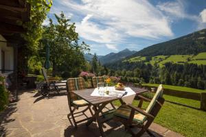 a table and chairs on a patio with a view of mountains at Pension Winklerkreuz in Alpbach