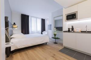 a white bedroom with a bed and a kitchen at Appartement T4 Le Courbin in Bordeaux