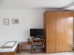 a bedroom with a wooden cabinet and a television at Litus in Njivice