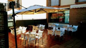 un restaurante con mesas y sillas blancas y sombrilla en Bar Posada Bemi, en Almorox