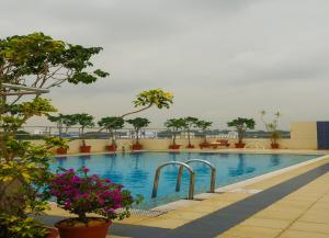 a swimming pool with trees and flowers in a building at Classic Sarovar Portico Trivandrum in Trivandrum