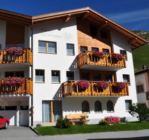 ein weißes Gebäude mit Balkonen und Blumen darauf in der Unterkunft Haus Gentiana in Samnaun