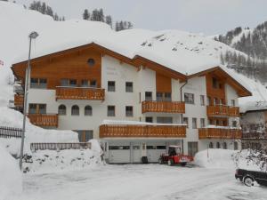 ein großes Gebäude im Schnee mit Parkplatz in der Unterkunft Haus Gentiana in Samnaun