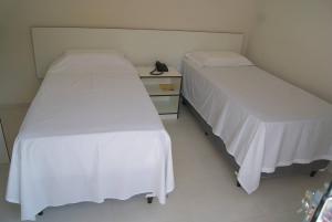 two beds sitting next to each other in a room at Hotel Nardy in Alvinópolis