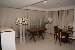 a dining room with a table and chairs and flowers at Hotel Nardy in Alvinópolis