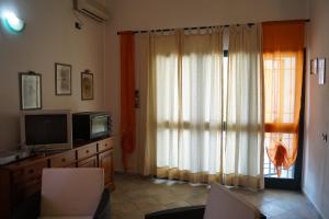 sala de estar con TV y ventana en Casa Su Catreathu en Orosei
