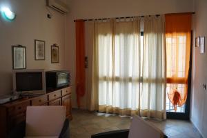 Una sala de estar con televisión y una ventana. en Casa Su Catreathu, en Orosei