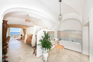 a bedroom with a bed and a tub and a table at Hotel Villa Gabrisa in Positano