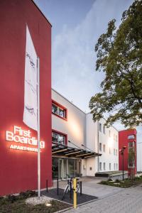 un edificio rojo y blanco con un primer signo de robótica delante de él en Apart-Hotel FirstBoarding Bayreuth, en Bayreuth