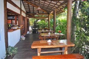 an outdoor patio with wooden tables and benches at Villa Cayana in Barra Grande