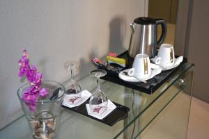 a glass table with wine glasses and a coffee pot at Hôtel de Guyenne in Talence