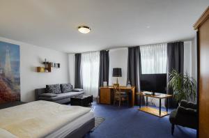 a bedroom with a bed and a desk with a television at Hotel Maxim in Langenfeld