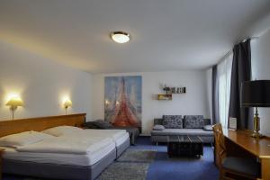 a bedroom with two beds and a living room with a couch at Hotel Maxim in Langenfeld