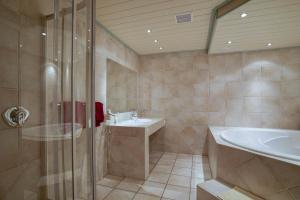 La salle de bains est pourvue d'une douche, d'un lavabo et d'une baignoire. dans l'établissement Hotel Maxim, à Langenfeld