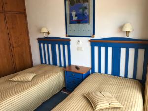 two beds in a bedroom with blue and white stripes at Residêncial Colaço in Alcoentre