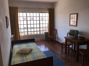 a bedroom with a bed and a desk and a television at Residêncial Colaço in Alcoentre