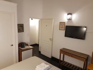 1 dormitorio con 1 cama y TV de pantalla plana en Hosteria El Colonial en Baradero