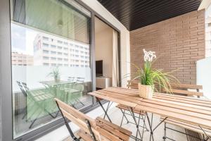 patio con mesa de madera y sillas en el balcón en La Serna Premium Center, en Málaga