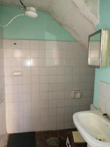 a bathroom with a sink and a white tiled wall at Homestay Jorge, Sucre in Sucre