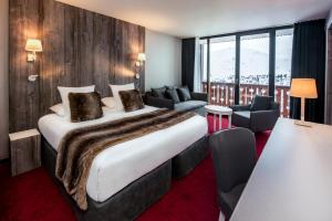 a hotel room with a large bed and chairs at Le Pic Blanc in L'Alpe-d'Huez