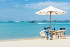 a table and chairs under an umbrella on the beach at NH Collection Samui Peace Resort in Bophut