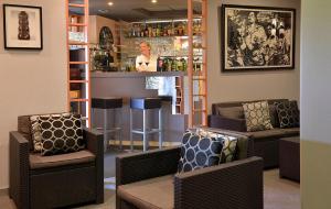 a bar with two chairs and a woman behind a counter at Logis Hotel Le Prieure in Saint-Marcel