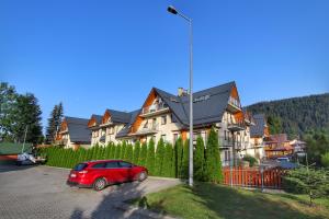 a red car parked in front of a large house at Zakopane Apartamenty LUX in Zakopane