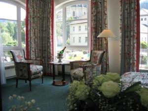 a room with a bed and chairs and a table and windows at Hotel Garni Aich in St. Blasien