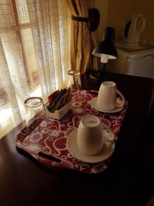 a table with two tea sets on top of it at Marlot Guest House in Polokwane