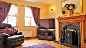 a living room with a fireplace and a television at Saint Patrick's Cottages (Downpatrick) in Downpatrick