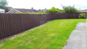 ogrodzenie w ogrodzie z zielonym trawnikiem w obiekcie Saint Patrick's Cottages (Downpatrick) w mieście Downpatrick