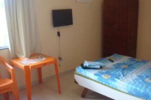 a bedroom with a bed and a table and a tv at stellamares apartamentos in Salvador