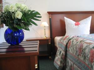um quarto de hotel com um vaso azul com flores numa mesa em Hotel Garni Aich em St. Blasien