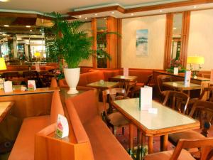 a restaurant with tables and chairs and a plant at Hotel Garni Aich in St. Blasien