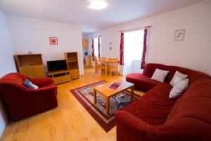 a living room with a red couch and a table at Apartments Branisko in Smokovce