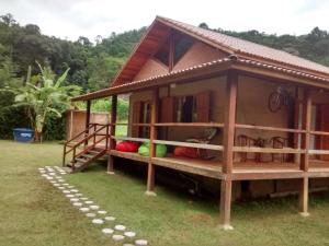 a small house with a porch on the grass at Casa do Bosque in Visconde De Maua