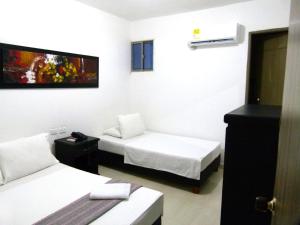 a room with two beds and a tv on the wall at Hotel Central in Sincelejo