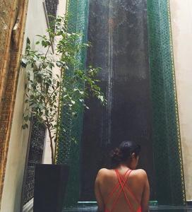 una mujer con un vestido rojo de pie junto a una planta en Riad Moullaoud, en Marrakech