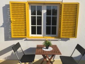 una mesa con sillas y una ventana con persianas amarillas en Casa Vila Sao & Pompeia, en Sesimbra